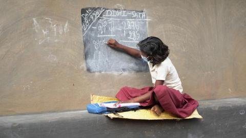 A small girl writing on the blackboard while the lockdown