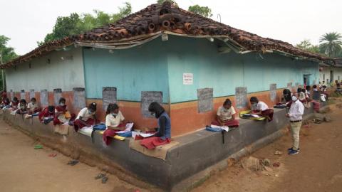 Student studying outside of the mud house to continue their class while covid-19